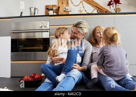 Grand-mère, la mère et les filles assis sur plancher de la cuisine, Banque D'Images