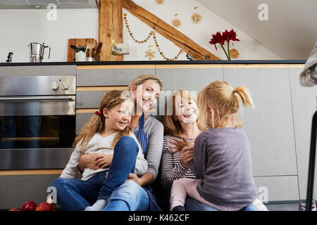Grand-mère, la mère et les filles assis sur plancher de la cuisine, Banque D'Images