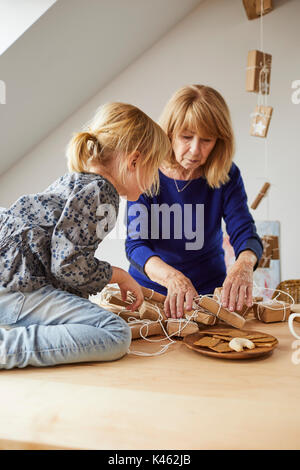Grand-mère et sa petite-fille à la maison confortable tout en ouvrant dans le temps de Noël Banque D'Images