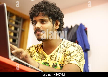 Young man sitting at desk and looking at laptop Banque D'Images