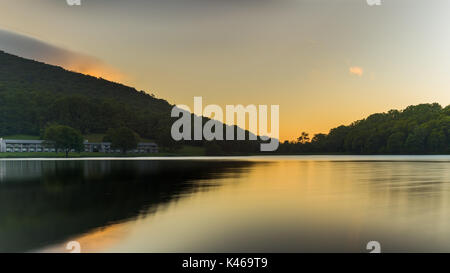 Le soleil se brise l'horizon mais toujours obscurci par les montagnes Blue Ridge de la création d'une lueur dorée sur le lac un dans le ciel Banque D'Images