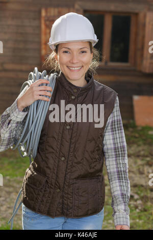 Confident female wearing hard hat en maintenant le rouleau de fil Banque D'Images