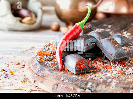 Morceaux de chocolat avec des piments sur une table en bois, d'épices, selective focus Banque D'Images