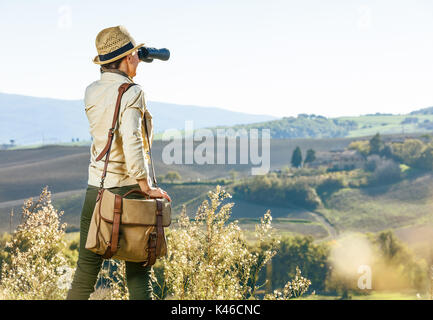 Découvrir une vue magique de la Toscane. Vu de dos randonneur avec sac femme profitant de la Toscane à la vue dans la distance avec des jumelles Banque D'Images