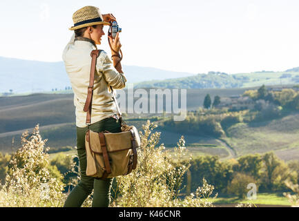 Découvrir une vue magique de la Toscane. Vu de dos femme randonneur dans hat randonnées en Toscane en prenant des photos avec l'appareil photo rétro Banque D'Images