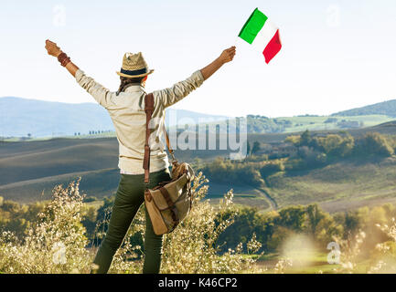 Découvrir une vue magique de la Toscane. Vus de derrière, jeune femme avec sac randonneur sur Toscane randonnée pédestre avec drapeau italien réjouissance Banque D'Images