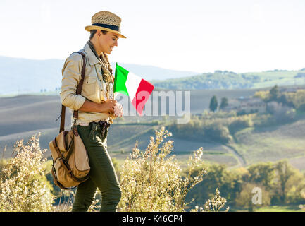 Découvrir une vue magique de la Toscane. smiling woman in hat randonneur aventure avec drapeau italien bénéficiant vue Toscane Banque D'Images