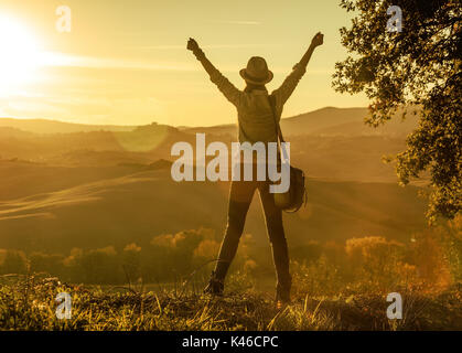 Découvrir une vue magique de la Toscane. Vu de dos femme sac Randonneur admirant le coucher du soleil avec en Toscane et de réjouissance Banque D'Images