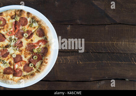 Vue de dessus de délicieuses pizzas fraîches sur plaque blanche sur table en bois Banque D'Images