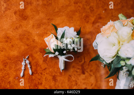 Boucles d de la mariée, boutonnière et bouquet de mariée sur fond de bois rustique Banque D'Images