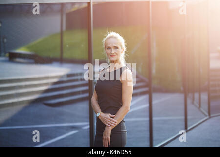 Le Portrait of mature businesswoman standing in front of édifice moderne en verre. Banque D'Images