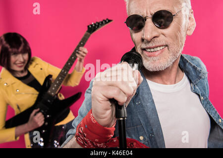 Close-up portrait of senior couple élégant chanter dans un microphone et playing electric guitar Banque D'Images