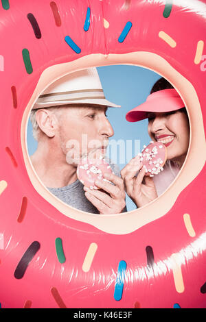 Portrait of elderly couple manger des beignets sucrés en tube de natation Banque D'Images