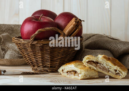 Morceaux de tarte aux pommes faite maison et des ingrédients biologiques frais dans le panier sur la table rustique en bois Banque D'Images