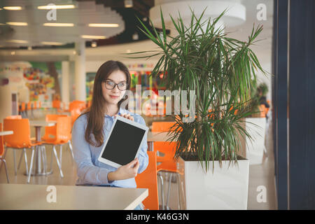 Portrait de jeune femme bespactacled holding tablet assis au café. Banque D'Images