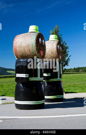 Deux modèles de pompiers faits de bottes de foin à l'extérieur de la station de pompiers en Esternberg & Augsburg, Haute Autriche, et Bavière, Allemagne. Banque D'Images