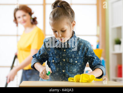 Famille heureuse nettoie la chambre. Mère et son enfant fille faire le nettoyage dans la maison. Une femme et un petit enfant fille essuya la poussière aspirée et th Banque D'Images