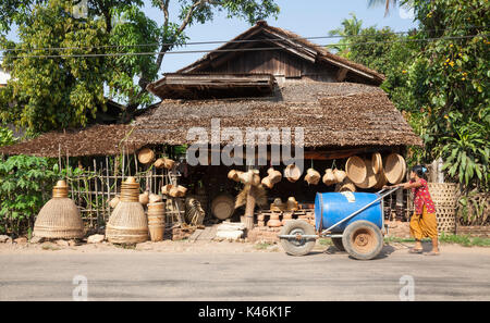 Femme de l'eau pousse passé panier panier village shop in rural Kadan Kyun, Myanmar Banque D'Images