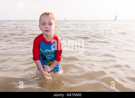 Un enfant de quatre ans garçon debout dans la mer à Southend-on-Sea, Essex, UK Banque D'Images