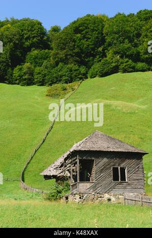 Ancienne maison en bois avec Green Grass Hills dans l'arrière-plan Banque D'Images