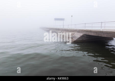 Un quai sur un lac au milieu du brouillard Banque D'Images