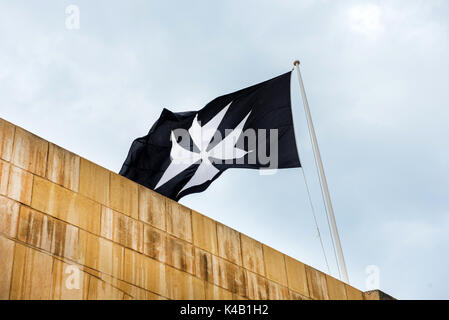 Symbole de l'Ordre de Saint Jean, la croix de Malte sur un drapeau noir Banque D'Images