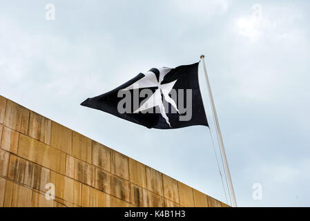 Symbole de l'Ordre de Saint Jean, la croix de Malte sur un drapeau noir Banque D'Images