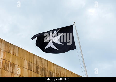 Symbole de l'Ordre de Saint Jean, la croix de Malte sur un drapeau noir Banque D'Images