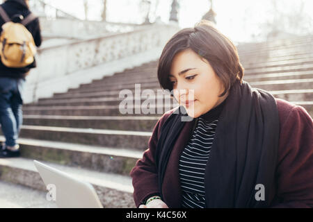 Jeune femme à l'aide de l'extérieur ordinateur - femme d'affaires, travail à distance, technologie concept Banque D'Images