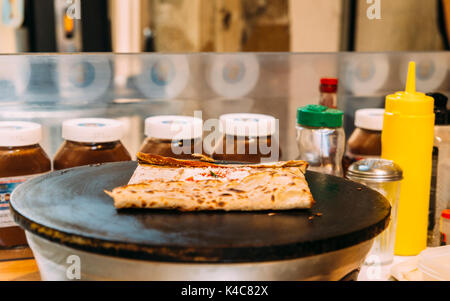 La préparation d'un snack-français composé d'une crêpe salée, également connu sous le nom de 'galete". Celui-ci est faite avec du fromage et de la sauce tomate, mais peut aussi être sucré wi Banque D'Images