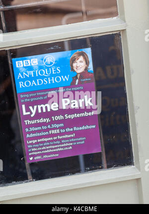 Un signe ou une affiche dans une vitrine publicitaire de la BBC's Antiques Roadshow qui se tiendra à Lyme Park avec une photo de Fiona présentateur Bruce Banque D'Images