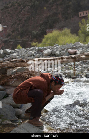 Berber man drinking de rivière, marché de setti fatma, vallée de l'Ourika, Maroc Banque D'Images