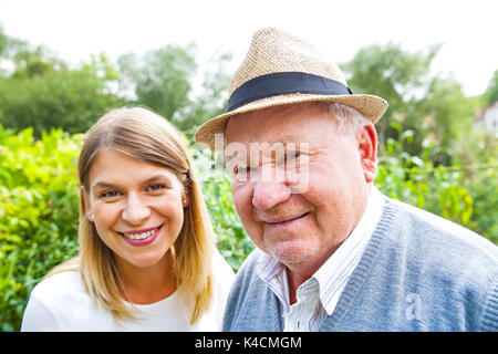 Smiling elderly man avec de belles jeune petite-fille posant dans le parc Banque D'Images