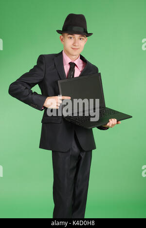 Portrait of confident businesswoman qui montre un doigt sur un ordinateur portable en formals isolés sur fond vert Banque D'Images