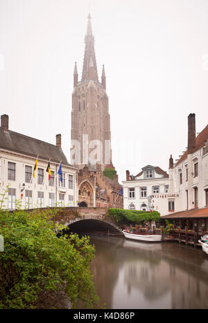 Vue de la tour de l'église de Notre Dame à Bruges lors d'un jour brumeux généralement avec reflet dans un canal. journée longue exposition shot. Banque D'Images