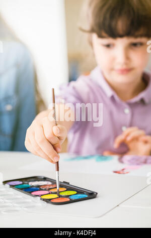 La mère et l'enfant de passer du temps ensemble à la maison, la jeune fille est la peinture avec pinceau et aquarelles Banque D'Images