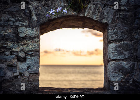 Coucher du soleil sur la mer à travers les ruines de fenêtre avec ciel dramatique et vue en perspective avec effet de lumière au bout du tunnel que voyage backgrou Banque D'Images