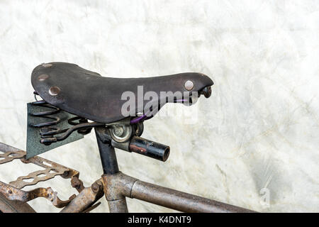 Fermé Vinatge selle de vélo s'appuyant sur mur de ciment. Banque D'Images