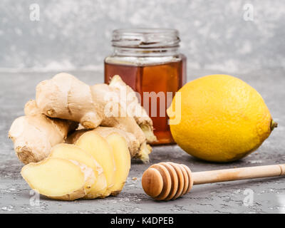 Vue rapprochée de la tranche de gingembre, racine de gingembre, citron et miel sur fond de béton gris Banque D'Images