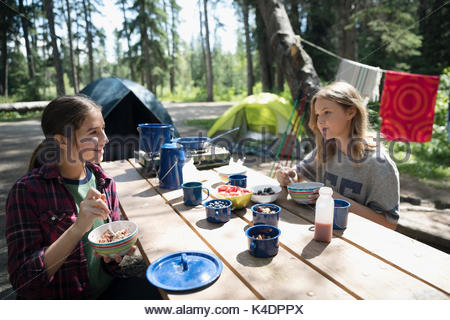 Teenage girl friends eating petit-déjeuner à l'école extérieure camping table de pique-nique