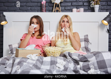 Portrait de deux amis au lit regarder film triste et de pleurer. Banque D'Images