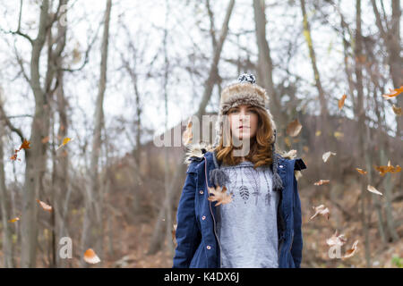 Close up of a young woman wearing winter hat entouré de feuilles. soft focus Banque D'Images