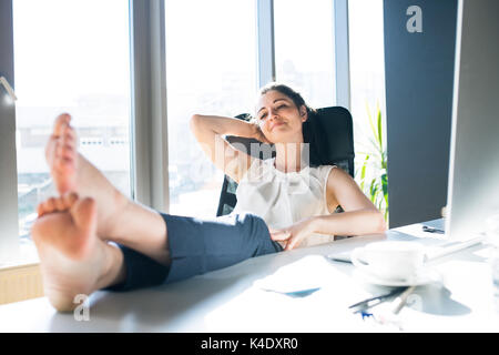 Portrait dans son bureau assis avec les jambes sur le bureau. Banque D'Images