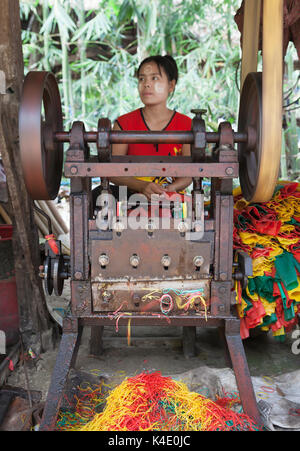 Bande en caoutchouc, de l'état de mon usine, le Myanmar. Exploitation des femmes machines guillotining latex coupe les tubes en caoutchouc pour créer des bandes de caoutchouc Banque D'Images