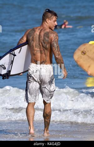 Surfer walking down beach dans l'exercice de surf Banque D'Images