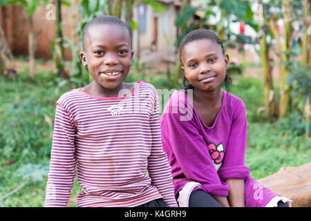 Deux belles jeunes filles de sourire et assis sur un tronc d'arbre tombé. Banque D'Images