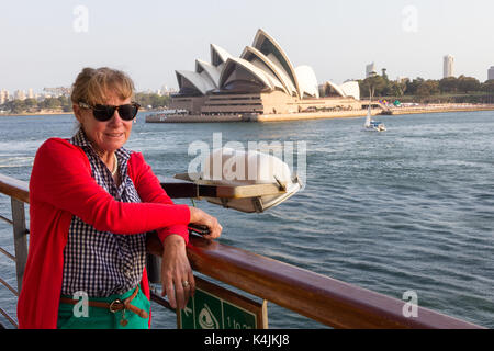 Senior woman passager sur le pont d'un navire de croisière du Port de Sydney, laissant passer l'Opéra Banque D'Images