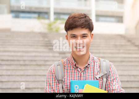 Asian male College student holding book in campus Banque D'Images