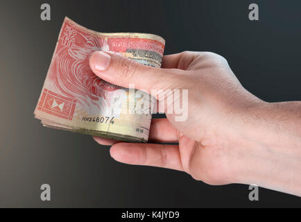 Un homme part remettre une liasse de plié hong kong dollar bank note sur un fond isolé Banque D'Images