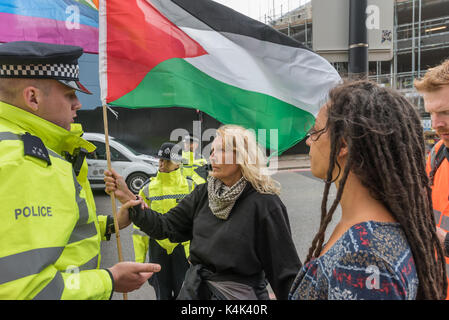 5 septembre 2017 - London, UK - London, UK. 5 septembre 2017. Un agent de police arests une femme qu'il vient brutalement tirés hors de la route où elle marchait lentement avec un drapeau palestinien à l'avant d'un camion. Les manifestants ont essayé d'arrêter les camions en direction de la porte ouest dans la plus grande foire aux armements détenus dans les Docklands de Londres sur la route sur le 'Pas de foi dans la guerre' journée de protestations organisées par divers groupes confessionnels. Avant mon arrivée il y avait eu un lock-in sur la route d'arrêter les livraisons en provenance d'établir la juste à travers la porte de l'Orient. Cela a été suivi par une réunion Quaker Banque D'Images